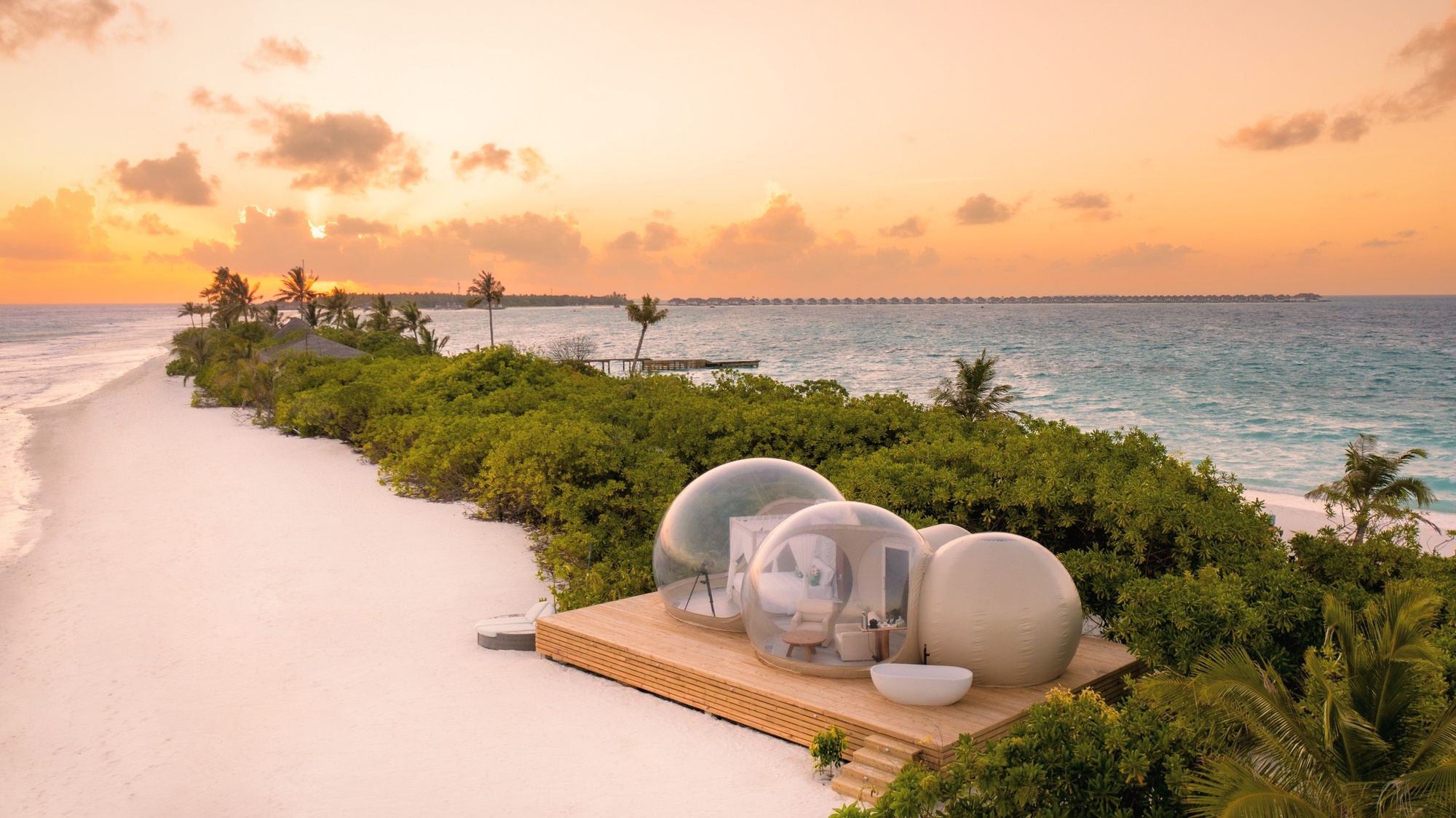 The Beach Bubble Tent on the sandbank at night. Transparent walls, open sky, the kind of experience that requires a booking and rewards the planning.