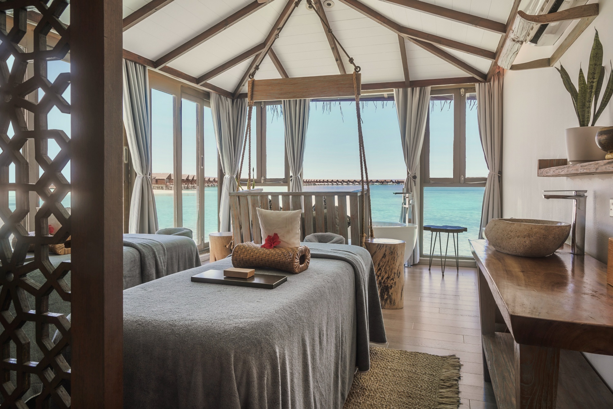 The spa treatment room. A single bed facing the water, natural materials, and the sound of the lagoon audible from inside.