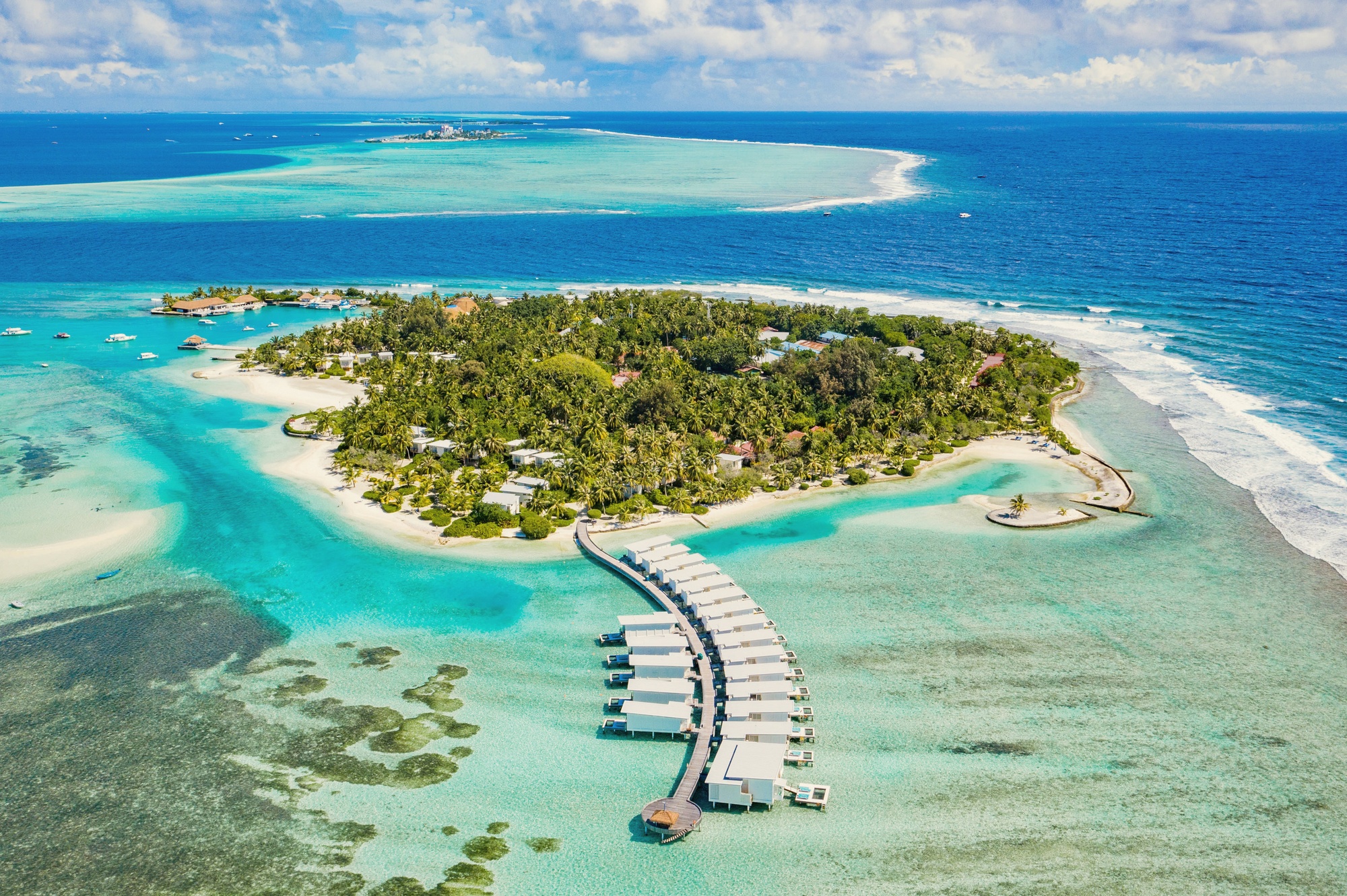 Kandooma Fushi from above. The island sits in South Malé Atoll, 35 km south of Malé, with the reef visible from the air on the eastern edge.
