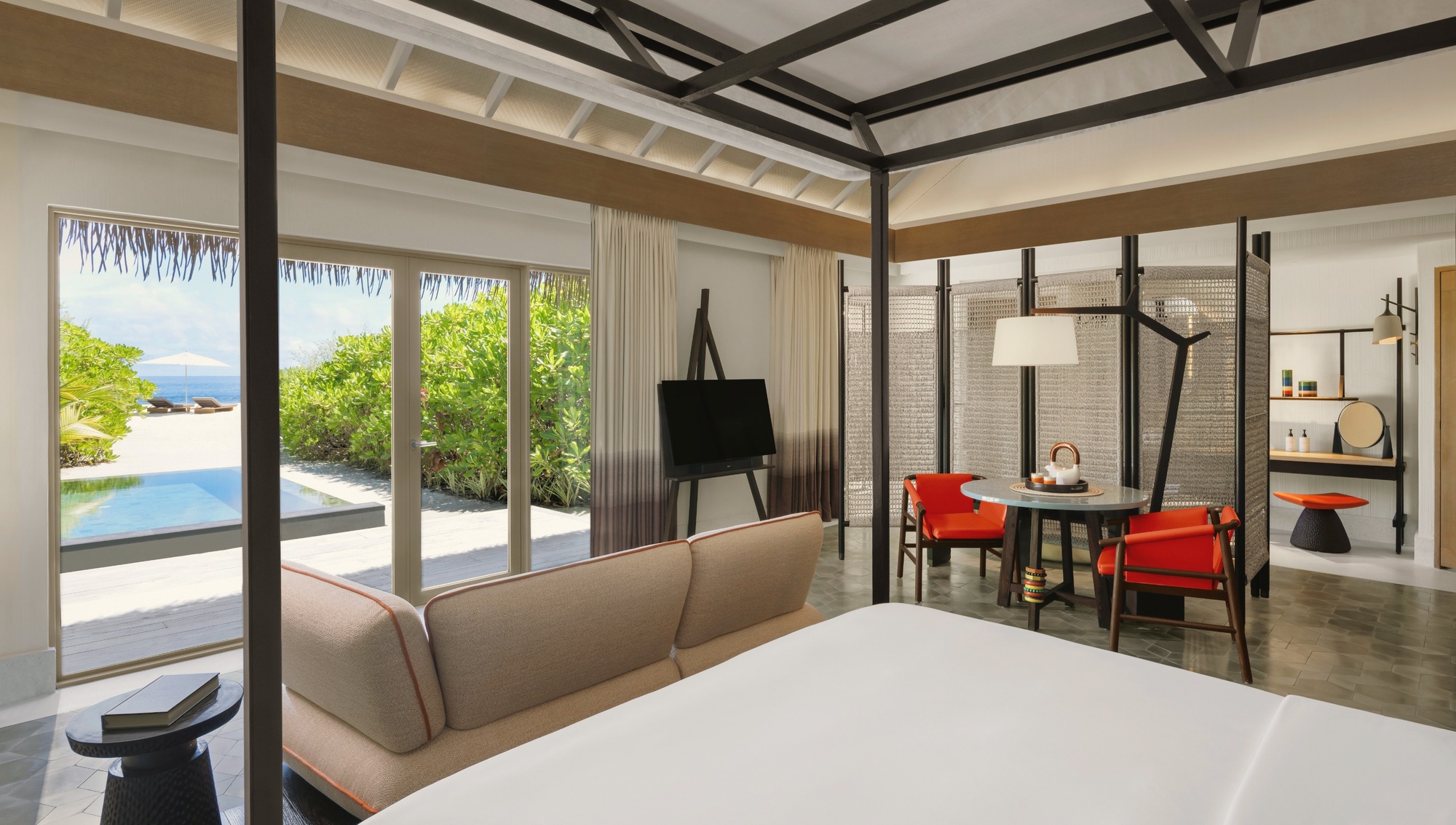 The interior of a beach pool villa. Private pool, direct beach access, and the lagoon framed by the villa's open-plan living space.