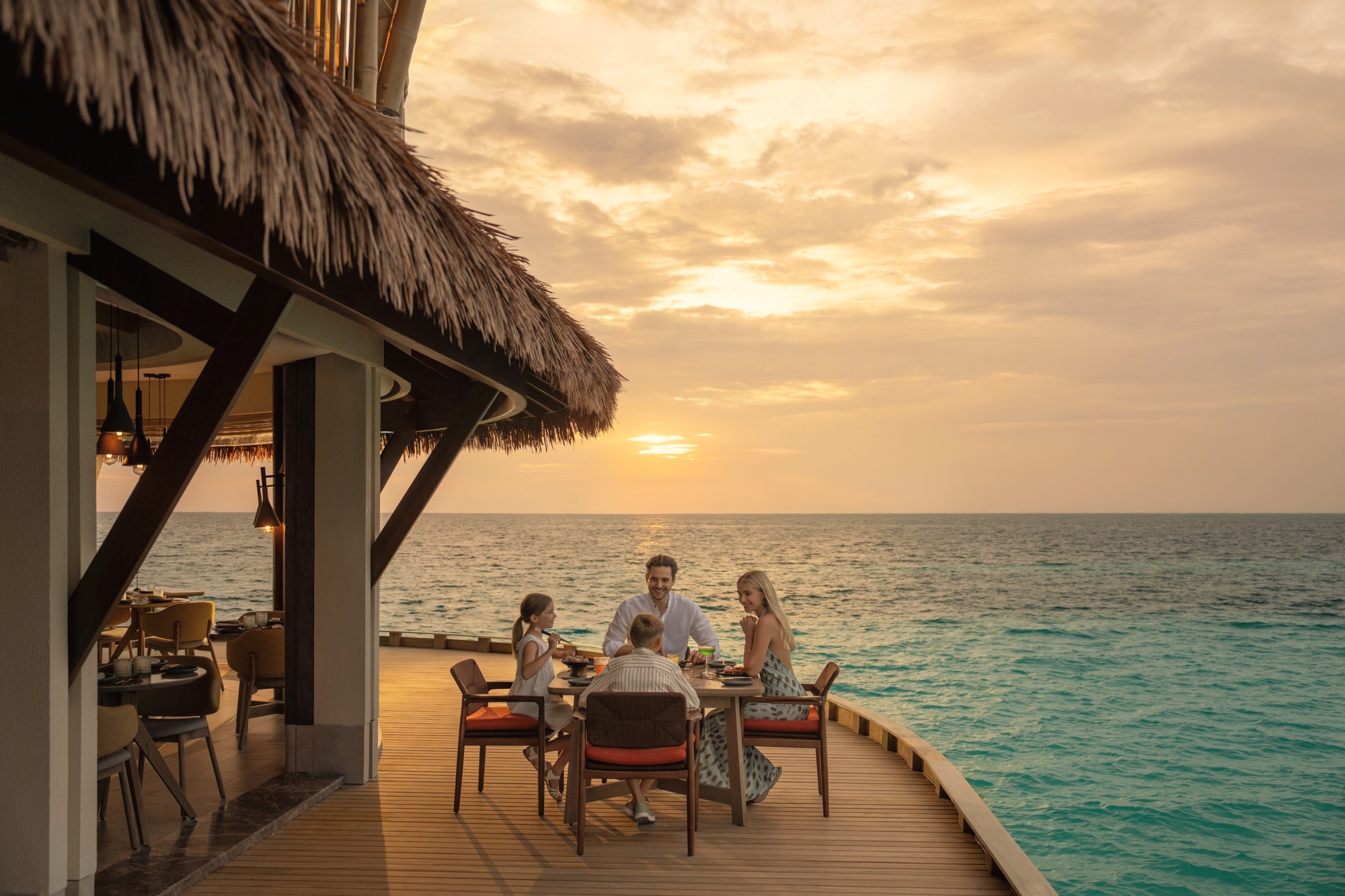 A dining setting on the water. The JW Marriott dining programme runs across multiple venues, with open-air tables positioned over the lagoon.