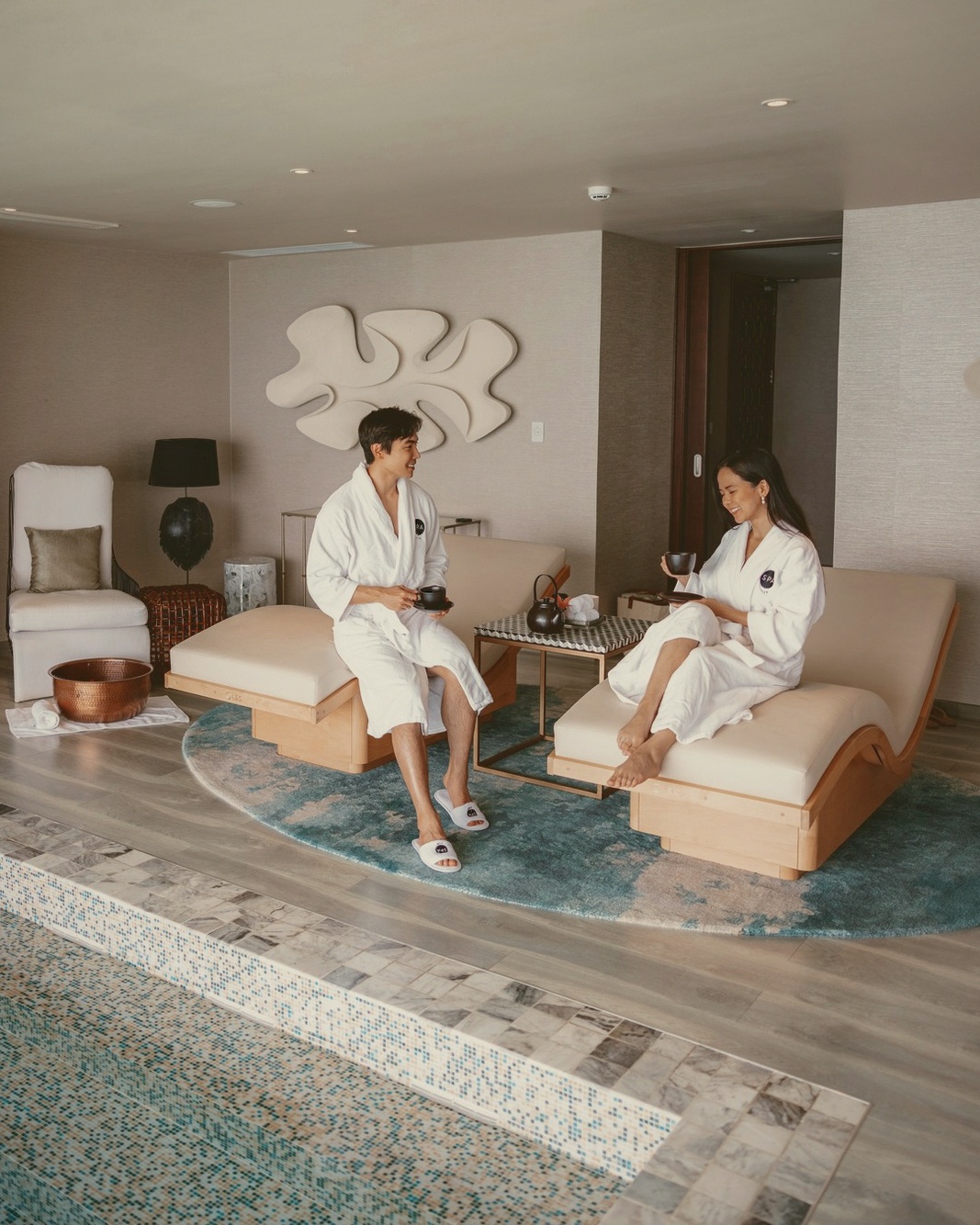 The overwater spa pavilion. Treatments are delivered above the water, with the lagoon visible through the floor panels beneath the treatment table.