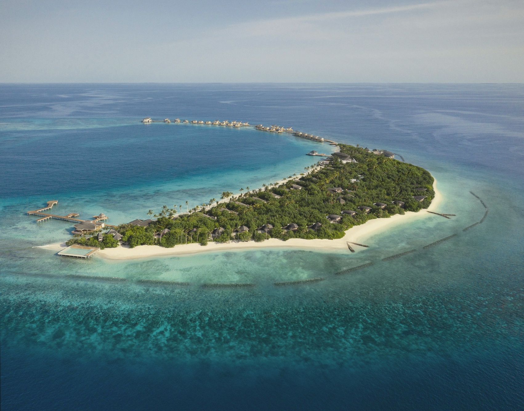The island from above. JW Marriott occupies its own private island in Shaviyani Atoll, with overwater and beach villa wings extending across the lagoon.