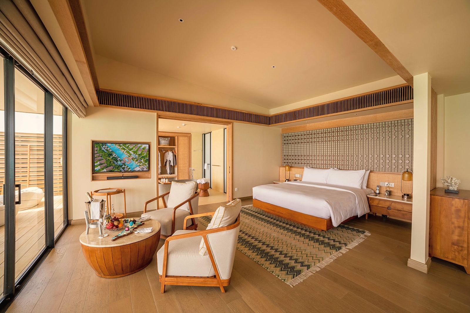 Inside a water villa. The interior opens directly onto the deck and the lagoon beyond, with clean lines and a calm palette.