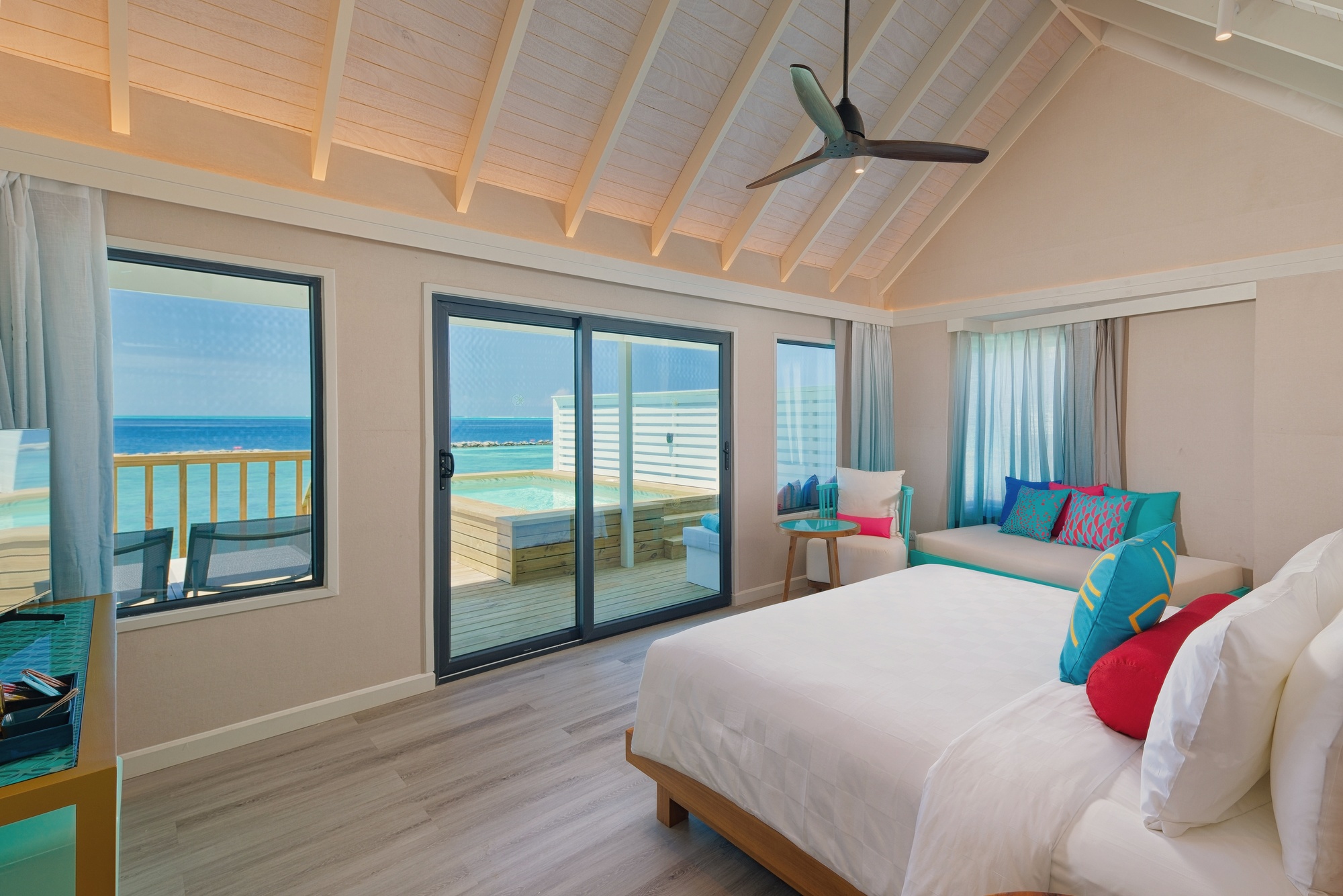 The interior of a sunset water villa. Warm tones, unobstructed views west across the Indian Ocean.