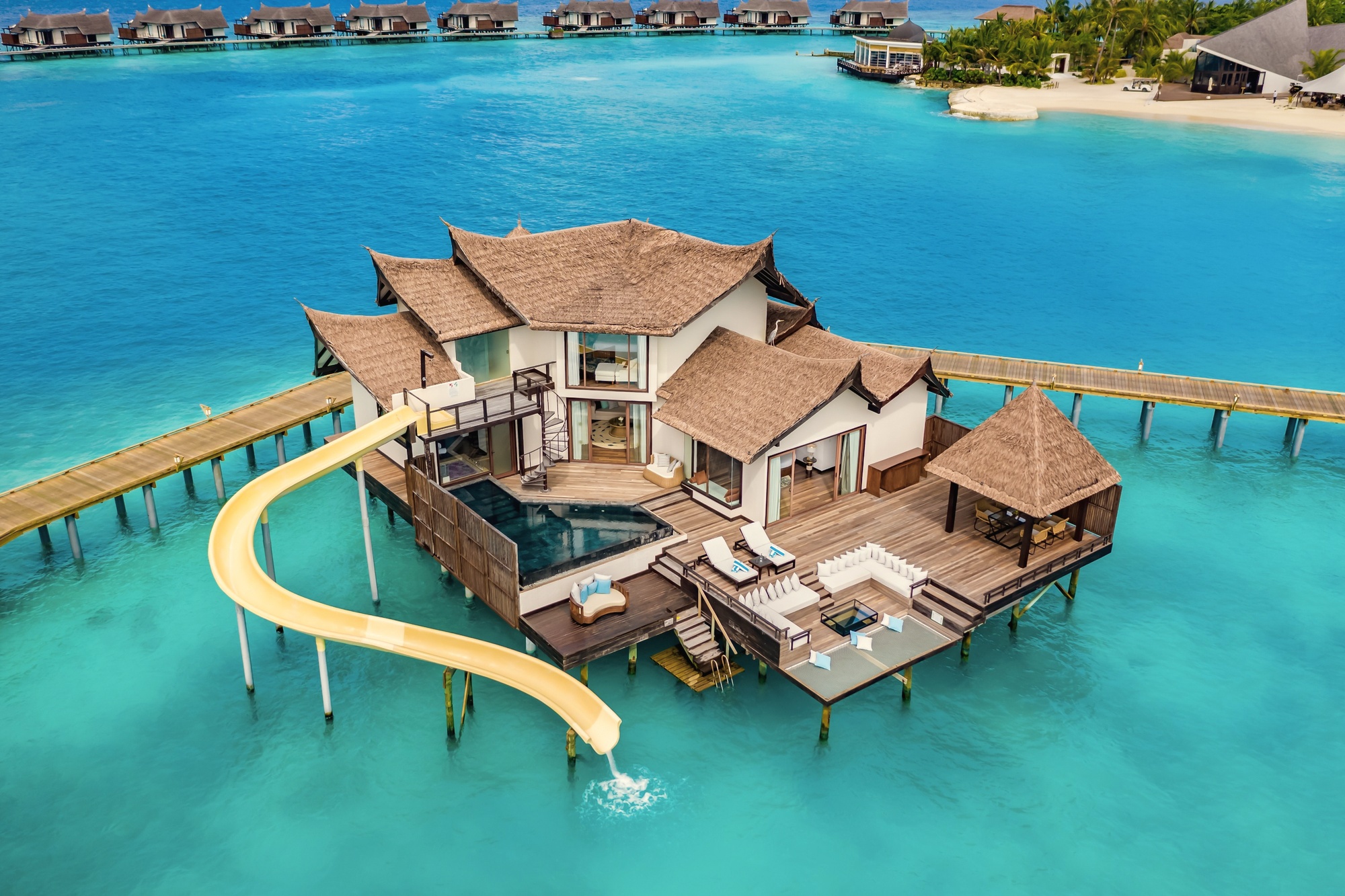 An overwater pool villa from the deck. The lagoon edge is the floor of the outdoor living space, with the pool at the waterline.