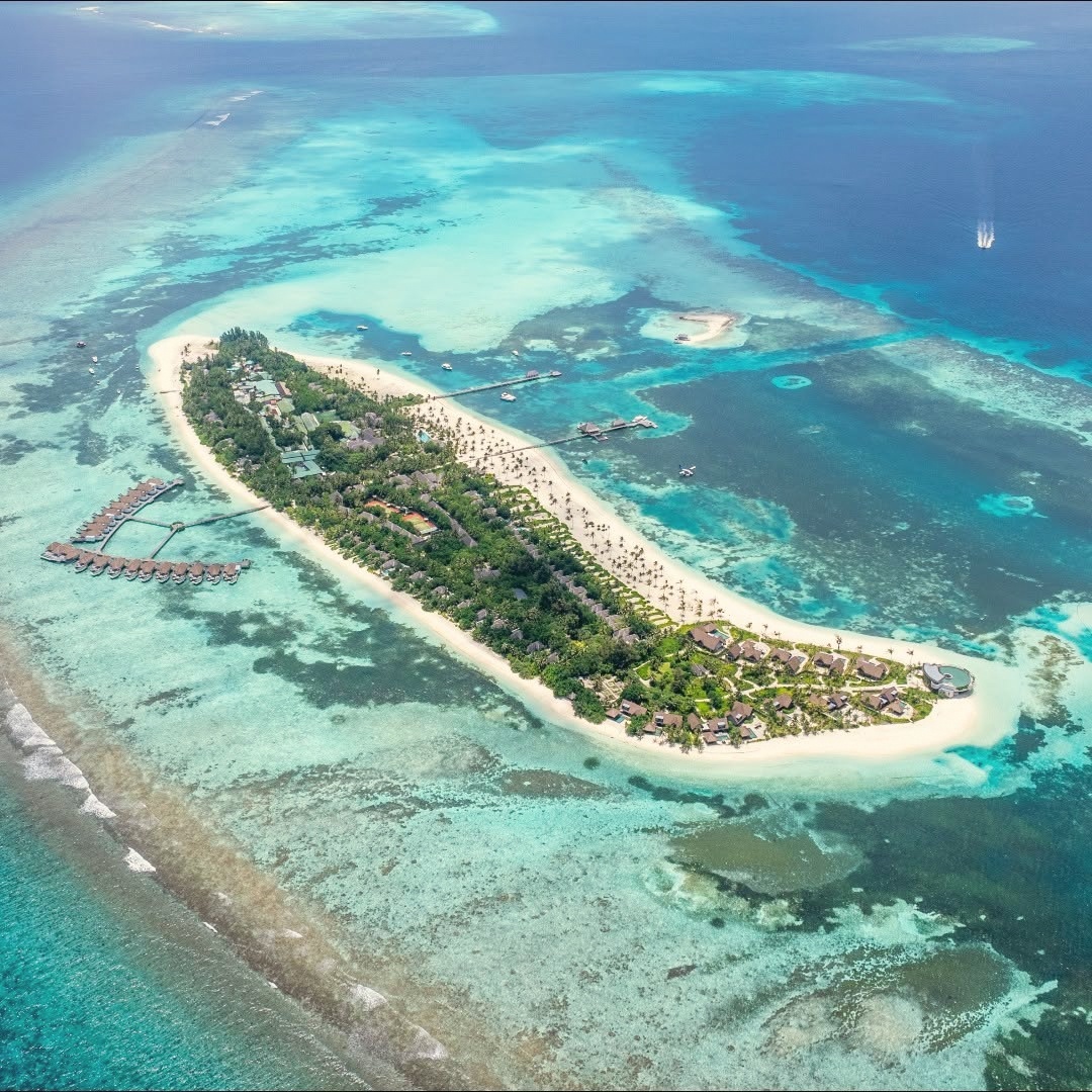 Kanuhura from above. The island sits in Lhaviyani Atoll, a private landmass with eighty-five villas spread across beach and overwater positions.