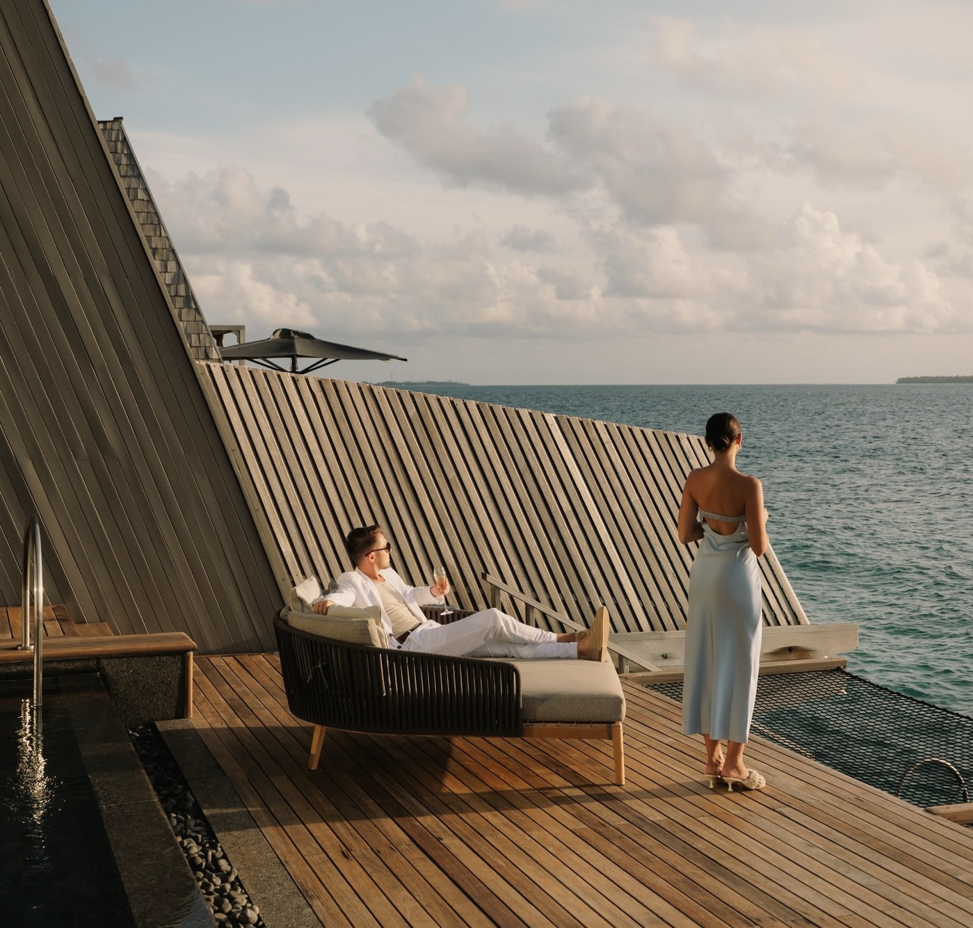 An overwater villa from the deck. The lagoon stretches to the horizon and the villa structure sits directly above clear water.