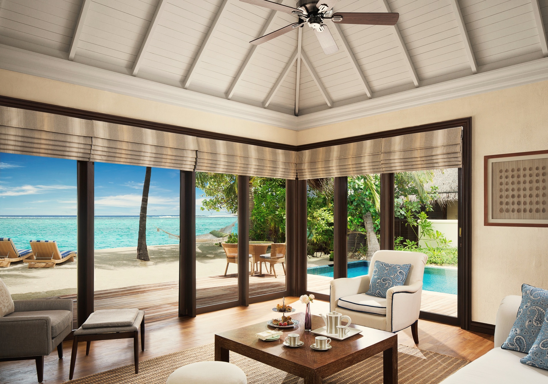 The interior of a beachfront suite. Taj Hotels finishes applied to a Maldivian island configuration, with the beach visible from the main living space.